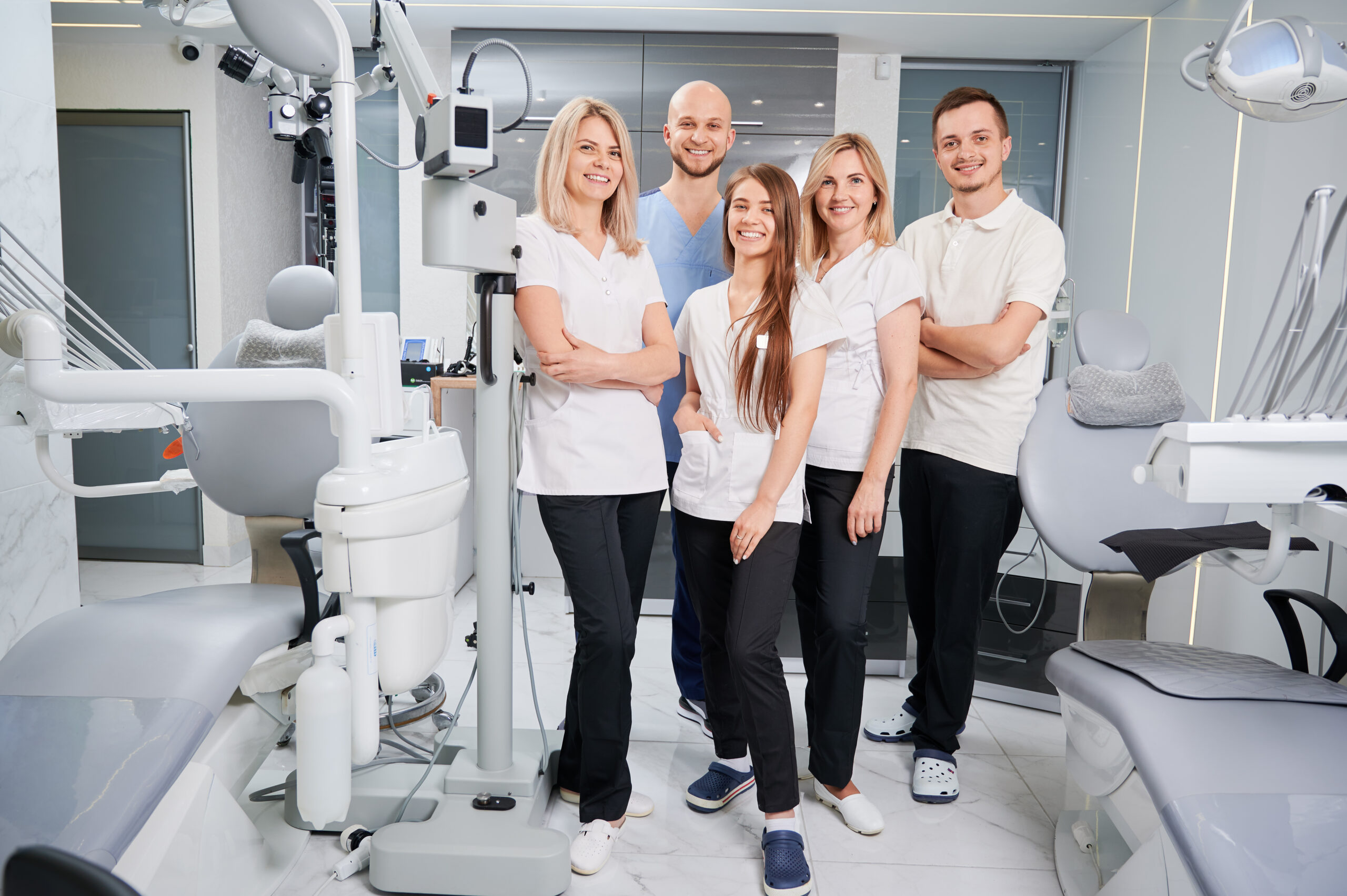 An orthodontic practice team of five standing together in the treatment area, the seats a dental team training plan has to cover